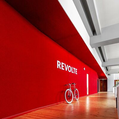 rote Teppichwand, weißer Revolte-Schriftzug, darunter weiß-rotes Revolte-Fahrrad